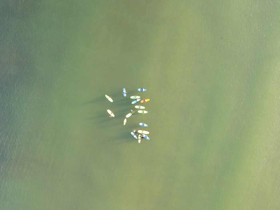 Vue aérienne de surfeurs sur des planches à pagaie dans l'eau calme de l'océan.