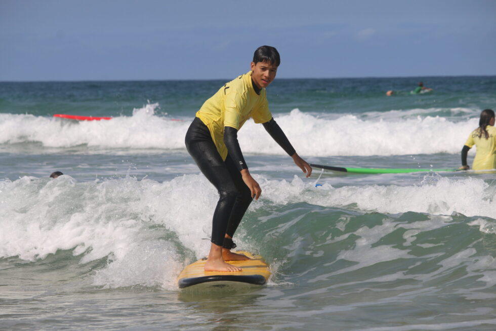 Un adolescent surfe sur une planche de surf jaune