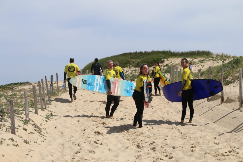 Surfeurs transportant des planches sur un sentier de plage sablonneuse