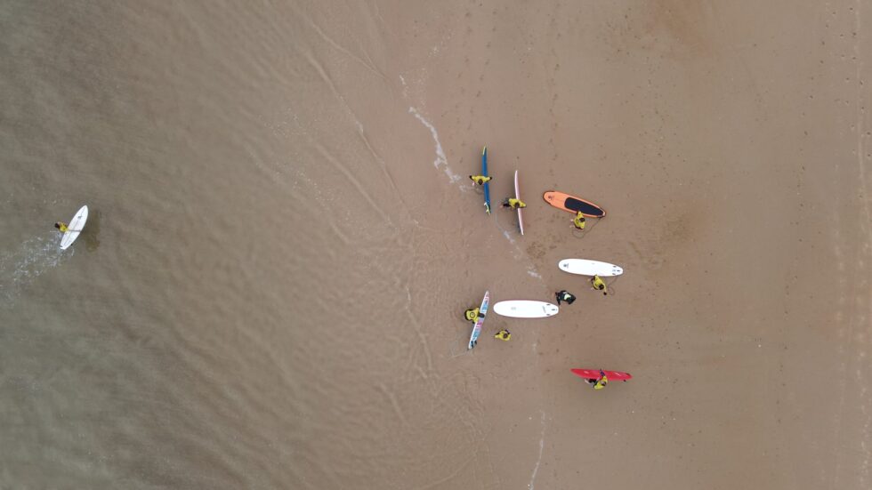 Vue aérienne de surfeurs et de planches de surf sur une plage de sable.
