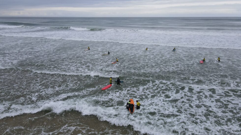 Cours de surf en cours : Instructeurs et élèves dans l'océan avec des planches de surf.