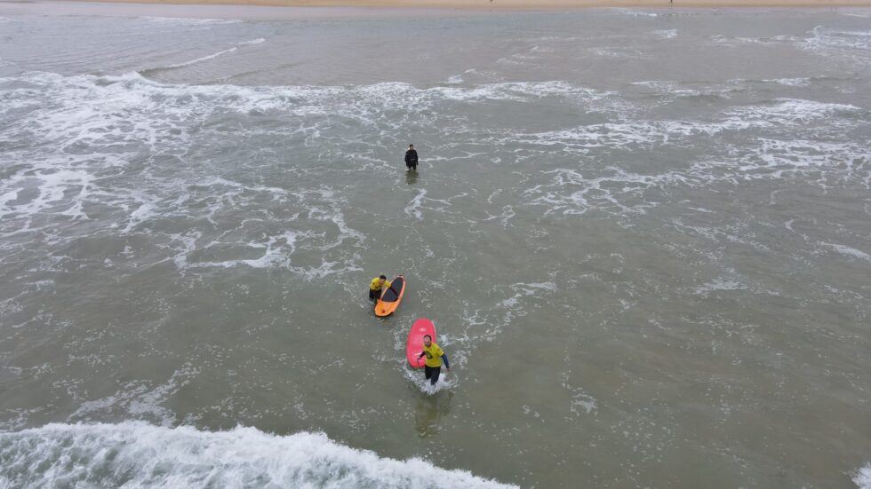 Trois surfeurs en combinaison se préparent à surfer dans l'océan.