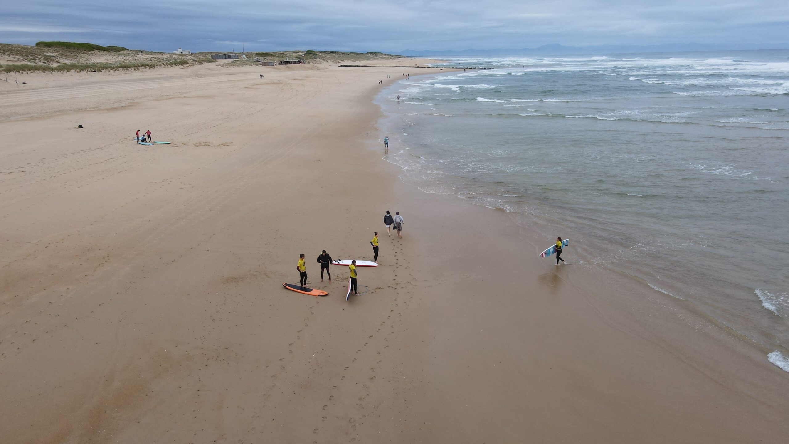 Playa de surf con clases particulares de 1h30: surfistas e instructor en la arena.