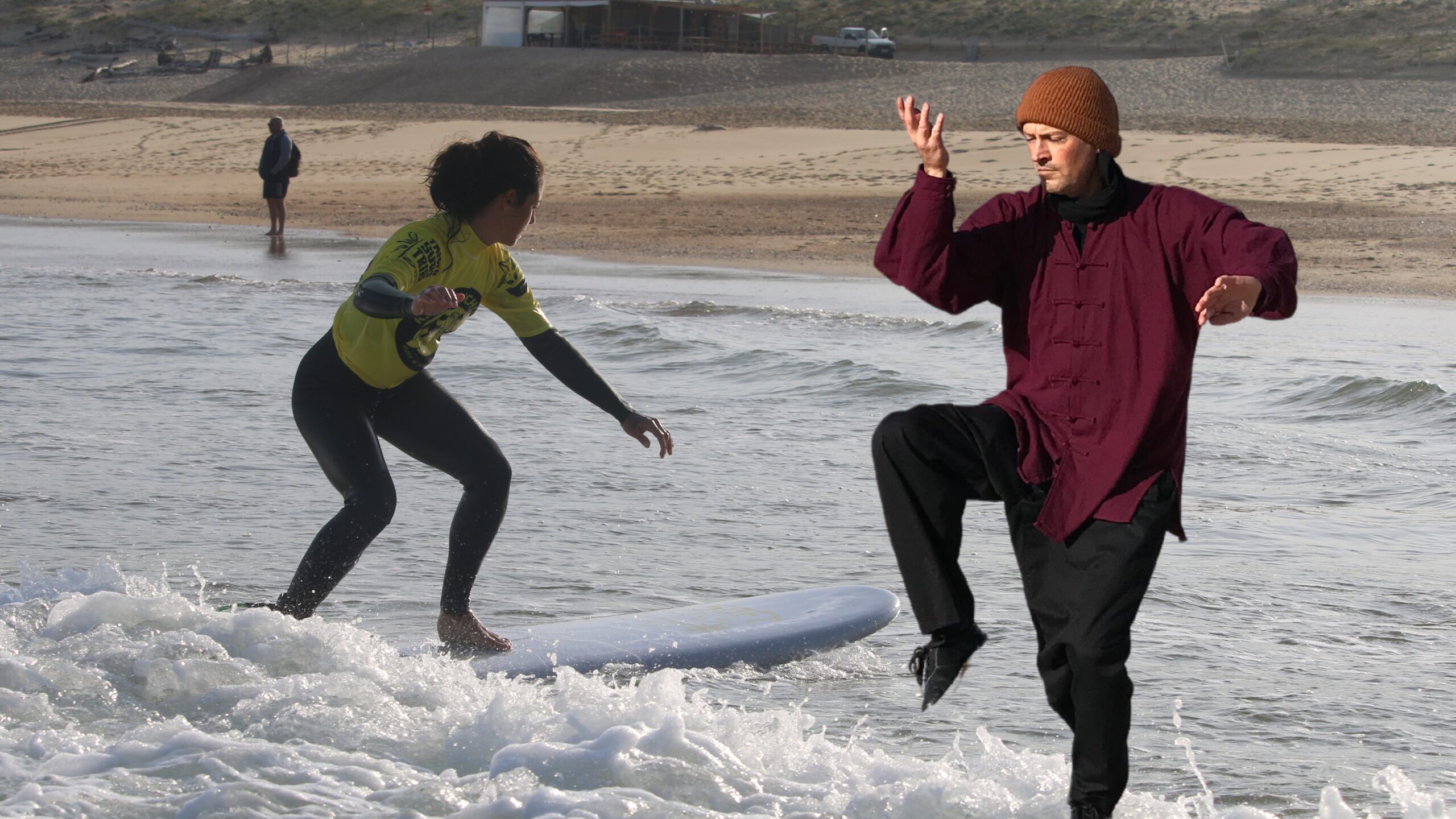 Surfeuse en action pendant un stage intensif de 5 jours, avec un homme en tenue de Tai-chi sur la plage.