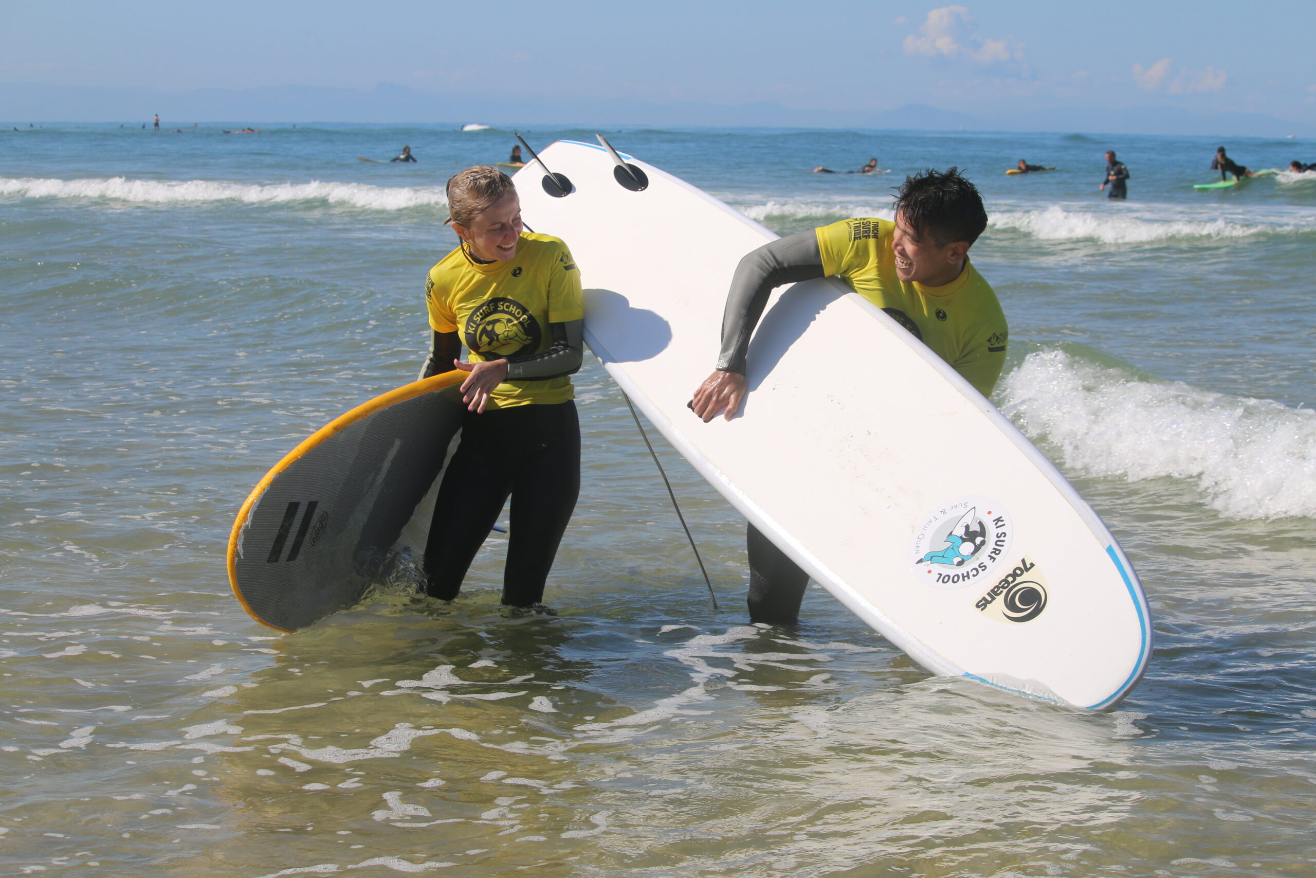 Deux instructeurs de surf portant des planches de surf à l'école de surf 7 Oceans.