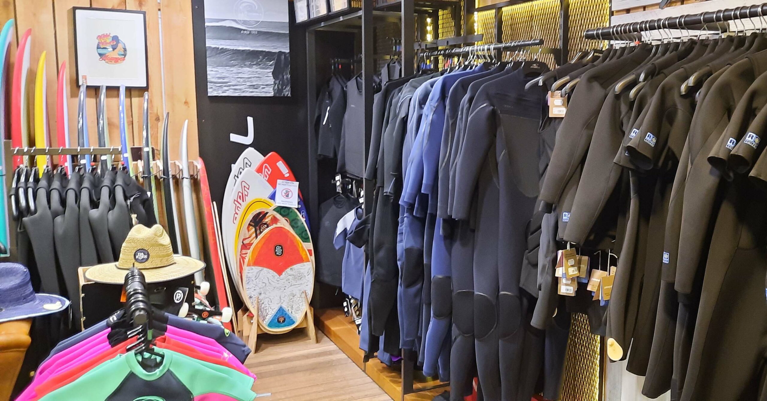 Surf shop display with wetsuits, surfboards, and accessories